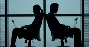 Picture of two people sitting back to back in chairs while using laptop